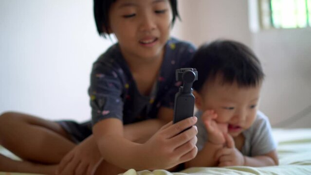 Sibling love of sister and little brother selfie together at bed