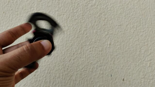 Footage of a black fidget spinner in shape of bat shot against blur background in summers during daylight. Fidget spinner is used as a stress reliver
