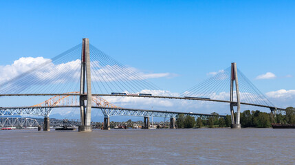 New Westminster, BC, Canada - April 22 2021 : SkyTrain passing the SkyBridge. A cable-stayed bridge...