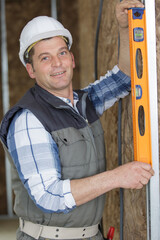 construction worker using spirit level on thermally insulated wall