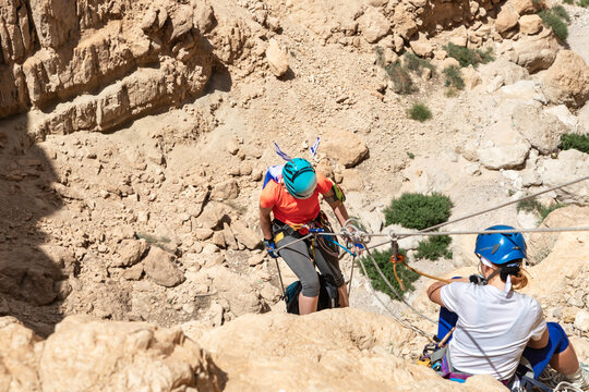 Experienced athlete on Israel Independence Day descending with equipment for rappel in mountains of Judean Desert, near Khatsatson stream, near Jerusalem, Israel.