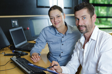 portrait of two techncians sat at a desk