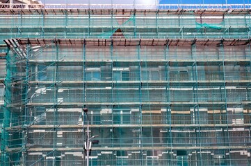 A large building that is under construction and is surrounded by scaffolding - special bridges for moving people on the site. 