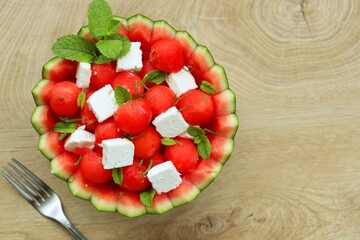 Watermelon Feta salad in watermelon basket with wooden table background.Fresh and healthy Italian summer salad.Top view.Copy space