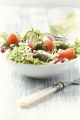 Salad with Green Olives, Tomatoes and Feta Cheese. Bright wooden background. Close up.