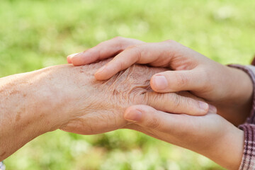 young woman holds the hand of an elderly pensioner