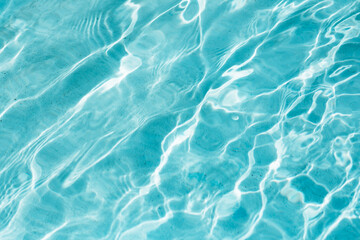 Blue water background of swimming pool or sea. Ripple water in swimming pool with sun reflection.
