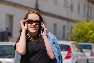 smiling woman with sunglasses and mobile phone on the street