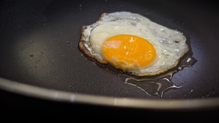 Egg fried on a hot black skillet.