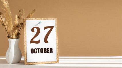 october 27. 27th day of month, calendar date.White vase with dead wood next to cork board with numbers. White-beige background with striped shadow. Concept of day of year, time planner, autumn month