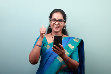 Portrait of a woman of Indian ethnicity holding a mobile phone with an excited face