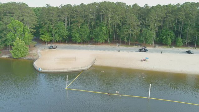 aerial footage of the silky brown sand of the beach surrounded by rippling lake water and lush green trees, grass and plants at Proctor Landing Park at Lake Acworth in Acworth Georgia USA