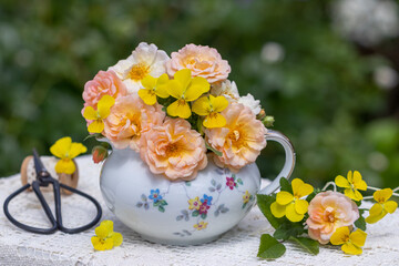 Blumenstrauß mit apricot Rosen und gelben Hornveilchen im vintage Milchkännchen