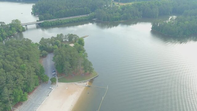 aerial footage of the silky brown sand of the beach surrounded by rippling lake water and lush green trees, grass and plants at Proctor Landing Park at Lake Acworth in Acworth Georgia USA