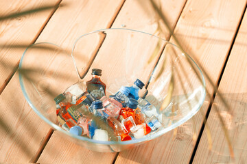 a bunch of tiny bottles of shots in a bowl of ice under palm branches on a wooden pier before the beach party starts