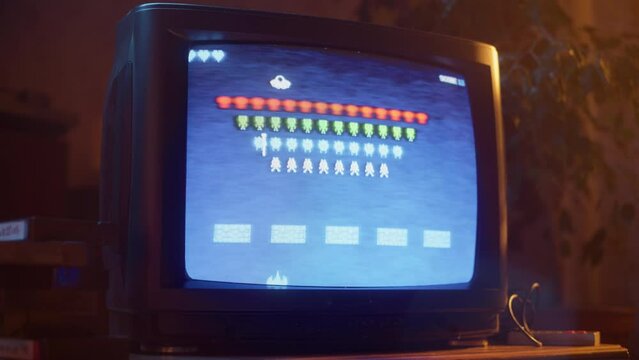 Close Up Footage of a Retro TV Set Screen with an 8 Bit 2D Eighties Inspired Console Arcade Video Game. Nostalgic Space Shooter Game, Player Battle with Swarm of Aliens and Wins.