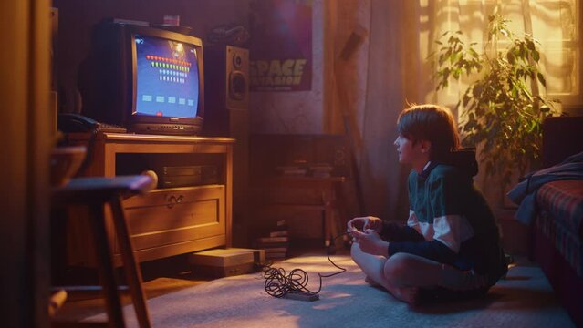 Handsome Child Playing 2D Arcade Space Shooter Video Game on a Console at Home in His Room with Eighties Interior. Young Boy Reaches End of Level and Wins. Nostalgic Retro Childhood Concept.