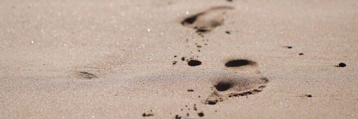 Fototapeta na wymiar Human foot prints on golden beach sand