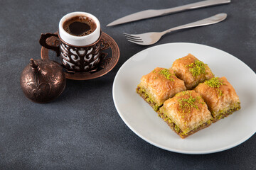 Pistachio baklava on a white plate with Turkish coffee

