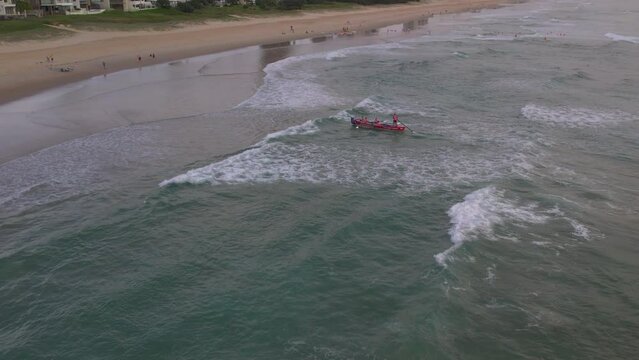 Aerial view of Mermaid Beach SLSC race boat coming into shore during a training session with the popular Gold Coast city in the background along Mermaid Beach Gold Coast QLD Australia