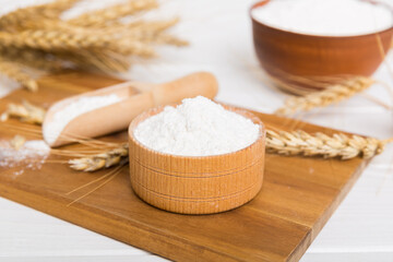 Flat lay of Wheat flour in wooden bowl with wheat spikelets on colored background. world wheat crisis