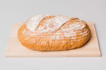 Freshly baked bread on cutting board against white wooden background. perspective view bread with copy space