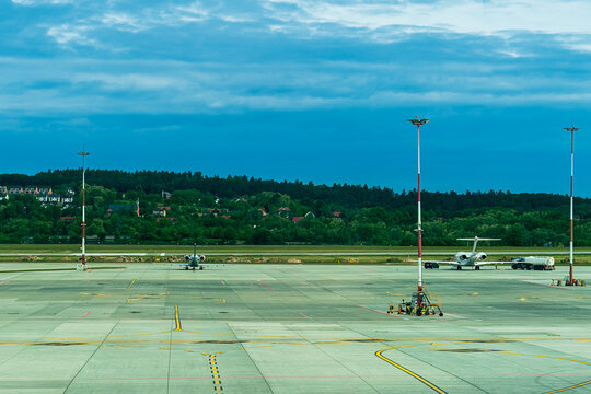 Two small private jets are parked at the airport in the morning against the backdrop of houses and forest in the suburbs under a cloudy sky, the jet is refueling.