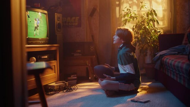 Nostalgic Retro Childhood Concept. Young Boy Watches American Football Match on TV in His Room with Dated Interior. Supporting His Favorite Team, Getting Excited When Players Score a Goal.