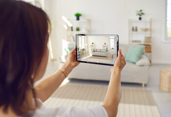 Person who plans on selling house or big spacious studio apartment takes photo on tablet device of...