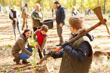 Familie und freiwillige Helfer pflanzen zusammen Bäume