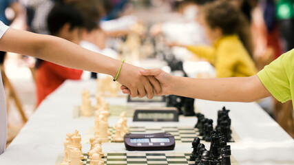 Handshake of the young people after the end of the chess match as a sign of sportsmanship and fair play. Concept of fairness, justice, equality, fidelity, honesty. - obrazy, fototapety, plakaty