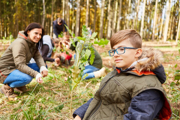 Junge und freiwillige Helfer beim Baum pflanzen im Wald