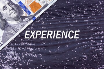 EXPERIENCE - word (text) on a dark wooden background, money, dollars and snow. Business concept (copy space).