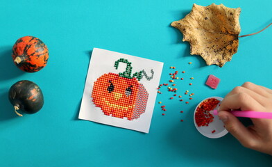 Image of cute orange pumpkin from diamond mosaic selective focus close-up, handmade and hobby
