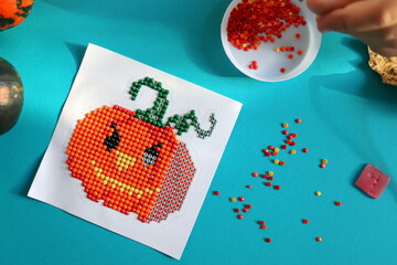 Image of cute orange pumpkin from diamond mosaic selective focus close-up, handmade and hobby