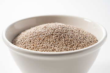 White chia seeds in a white bowl set against a white background.