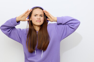 Naklejka premium an interested woman is standing on a white background in a purple tracksuit wearing a hood on her head with her hands on it looking around