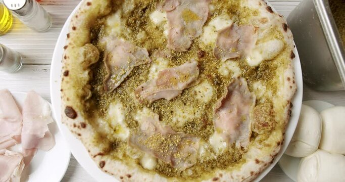 Pizza with Meat, Pesto, Cheese and Parmesan fresh out of the oven ready to eat. Delicious Italian pizza. Napoli Pizza. Food Service on white table and ingredient. Tasty Pizza with Cheese and Parmesan.