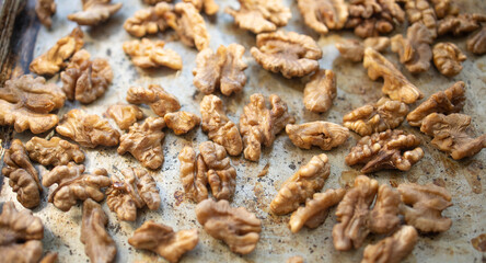 Roasted walnut lies on a metal baking sheet. Protein, healthy nuts, shortage of walnuts, more expensive snacks.