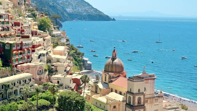 Street scape of Positano, located on the Tyrrhenian sea coast, Italy. Rows of residential buildings, church, greenery, boats in the distance