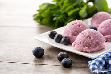 Blueberry ice cream scoops on wooden table	