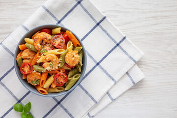 Homemade Tri-Color Penne Salad with Shrimp, Tomato and Basil Bread Crumbs in a Bowl, top view. Flat lay, overhead, from above. Copy space.