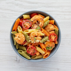 Homemade Tri-Color Penne Salad with Shrimp, Tomato and Basil Bread Crumbs in a Bowl, top view. Flat lay, overhead, from above.