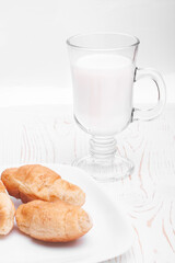 croissants in a plate close-up and a glass mug with milk on a white wooden background