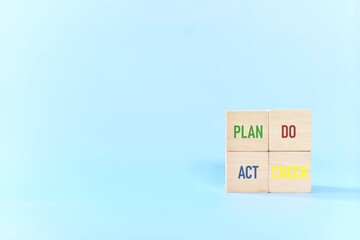 PDCA or Plan Do Check Act cycle method concept. Wooden blocks in blue background with copy space.