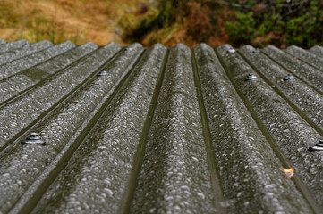 A corrugated roof falls away from the camera, the angle takes the rain with it