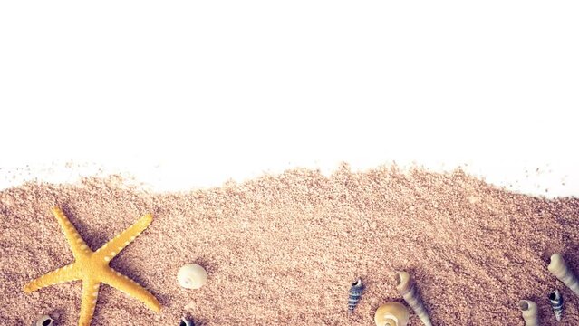 
stop motion of a sea wave that reveals a yellow starfish, conches and shells spread over the sand