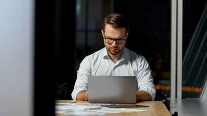 Young ceo typing message on laptop keyboard in office