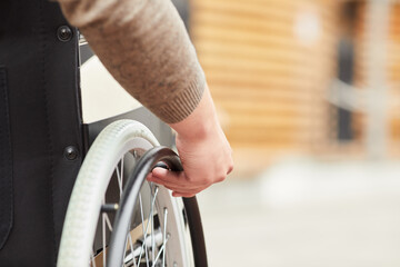 Obraz premium Close-up of unrecognizable man sitting in modern wheelchair and holding hand rims while spinning wheelchair outdoors