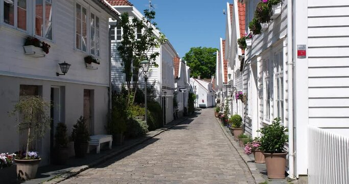 Stavanger, Norway. Street view of the old city in a sunny spring day. Street with traditional white wooden houses in Gamle Stavanger in Rogaland. Cobblestone road. 4K UHD 59,94fps ProRes 422 HQ 10 bit